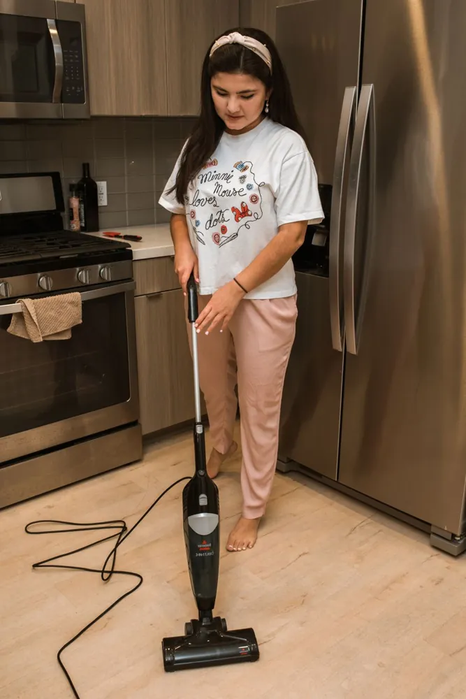 A woman vacuuming a kitchen floor